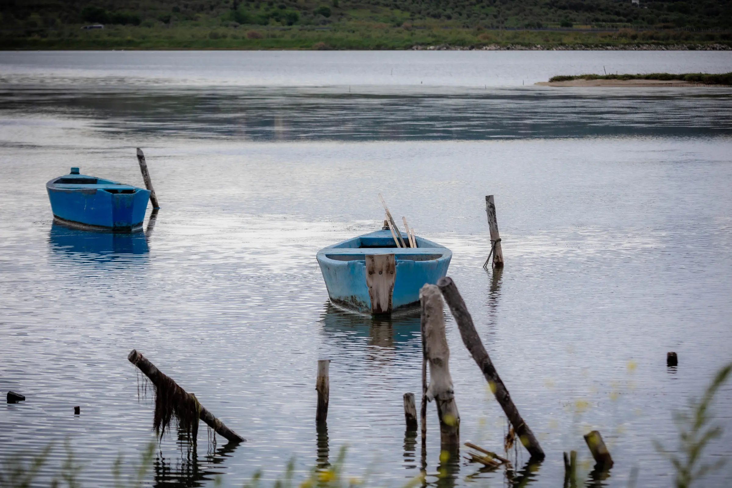 Zwei kleine Boote zwischen alten Holzpfählen am Rand der Lagune